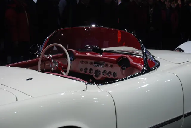 1953 Corvette cockpit showing the red bucket seats, dashboard, steering wheel, Powerglide selector, and passenger-side radio location.