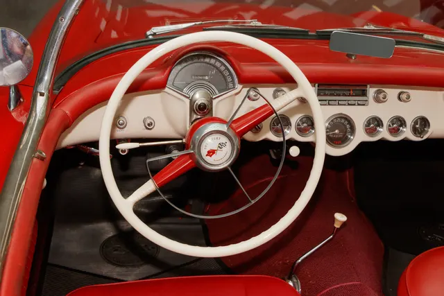 Dashboard detail showing the 140-mph speedometer, tachometer, auxiliary gauges, radio, steering wheel, and Powerglide selector.