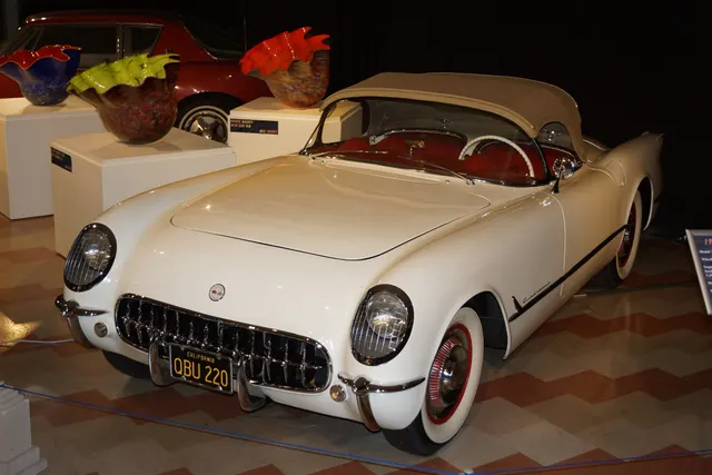 Museum-displayed Polo White 1954 Corvette with a beige folding top, retained as restoration and weather-equipment context rather than proof of another car's originality.