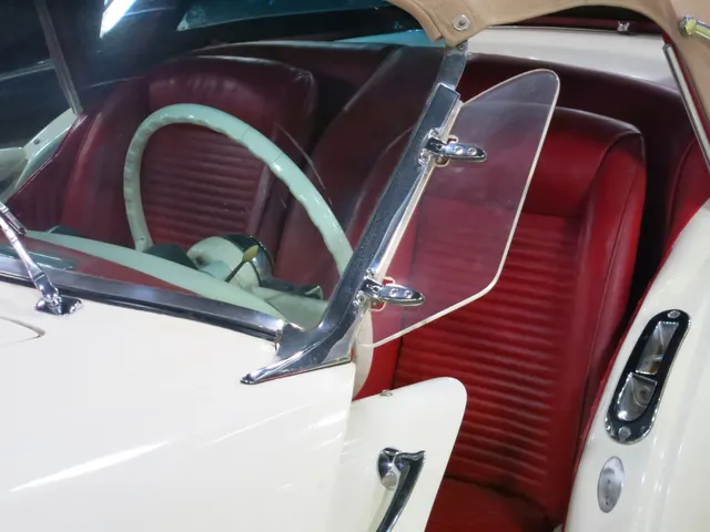 Cabin view showing the two bucket seats, color-keyed upholstery, steering wheel, wind wing, sliding-door opening, and top hardware.