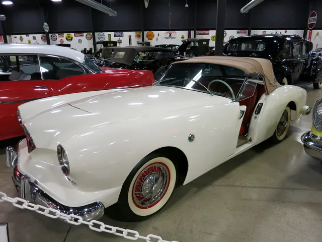 Front and side view of a Champagne Lacquer restored Darrin retained for body contours, grille, lighting, windshield, top, and sliding-door inspection context.