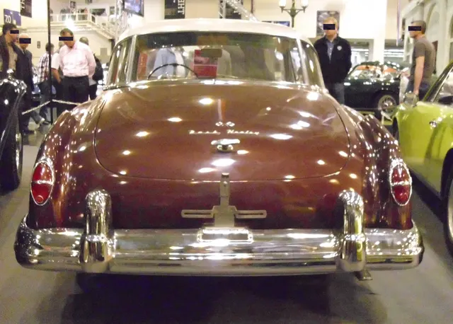 Rear view showing the later three-piece glass, reverse-slanted pillars, deck, lamps, bumpers, and Le Mans script; early final-year cars can instead have oval single glass.