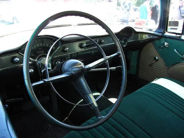 Stock-presenting Bel Air sedan cabin showing the bench seat, two-spoke wheel and horn ring, sweeping instrument cluster, dash trim, radio, and column shifter.