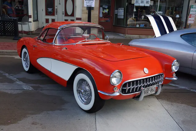 Restored Venetian Red 1956 Corvette with a contrasting cove and auxiliary hardtop; its aftermarket wire wheels make this restoration context rather than representative factory exterior media.