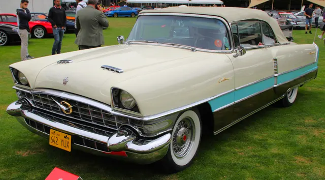 1956 Caribbean convertible front three-quarter view showing the hood scoops, grille, tri-color paint break, and Caribbean script