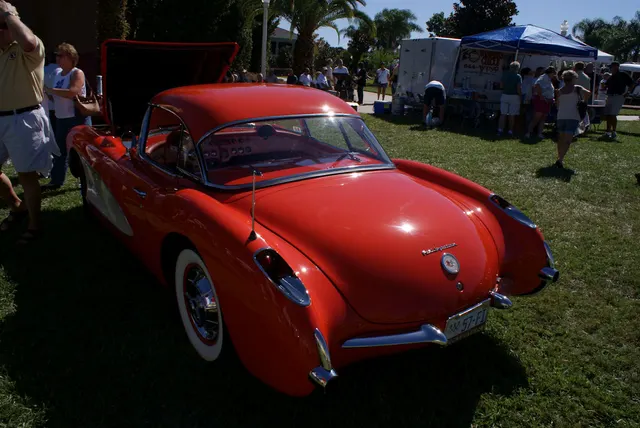 Left-rear view of a restored-stock 1957 Corvette showing rear body contours, lamps, bumper, wheel, and exhaust context.