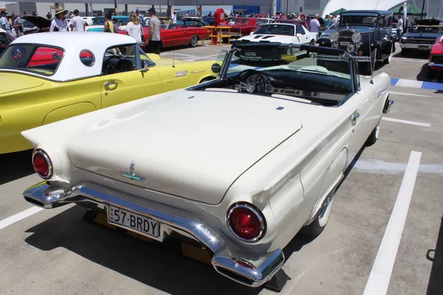 Open-car rear three-quarter view showing the lengthened deck, fins, round lamps, revised bumper, and two-seat cabin.