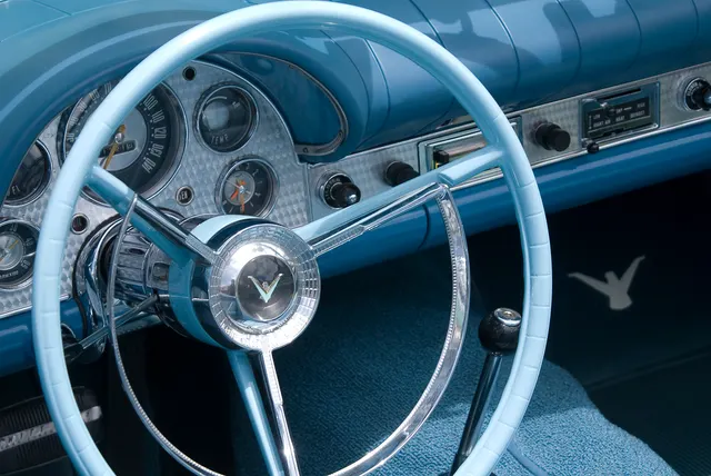Engine-turned dashboard detail with speedometer, tachometer, clock, fuel and temperature gauges, radio, and floor shifter.