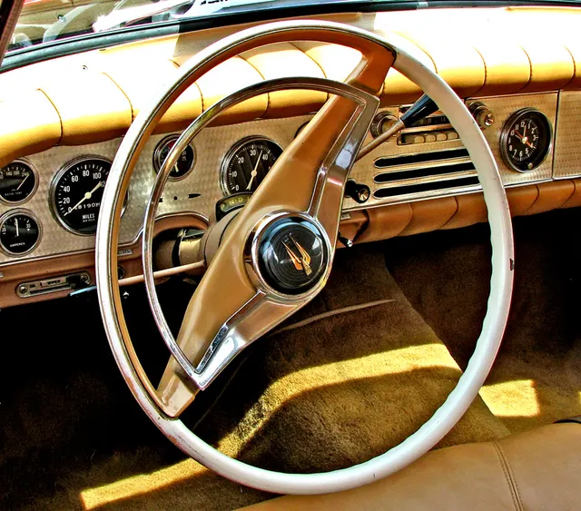 Exact-year dashboard view showing the leather trim, engine-turned instrument panel, steering wheel, speedometer, tachometer, clock, and auxiliary gauges.