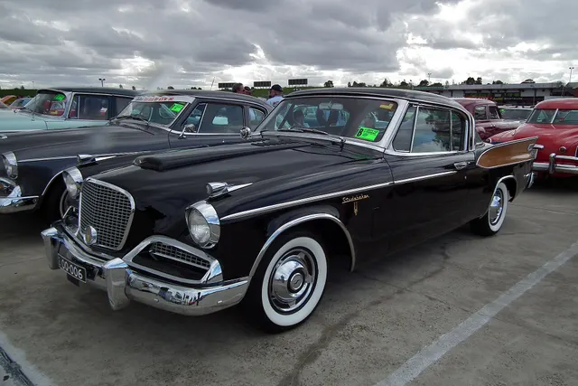 Exact-year Golden Hawk exterior view retained for body, roof, grille, hood, fin, trim, and wheel context; surrounding cars do not affect subject identity.