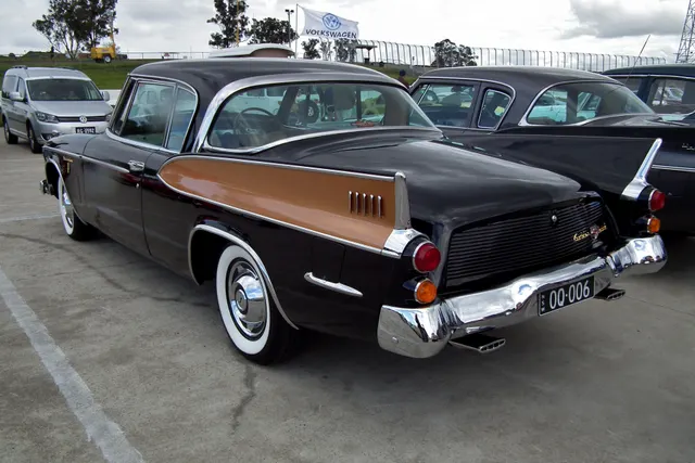 Rear three-quarter view of an exact-year Golden Hawk showing the pillarless roofline, fins, inset side panels, tail lamps, bumper, brightwork, wheel covers, and whitewall tires.