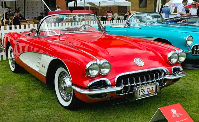 Roman Red 1959 Corvette in front three-quarter view with white coves, quad headlamps, and the model year's clean hood.