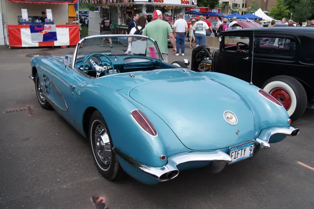 Rear three-quarter view of a Frost Blue 1959 Corvette, showing the clean trunk lid, split bumpers, and dual exhaust outlets.