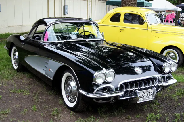 Tuxedo Black 1959 Corvette with silver coves, removable hardtop, full wheel covers, and whitewall tires.