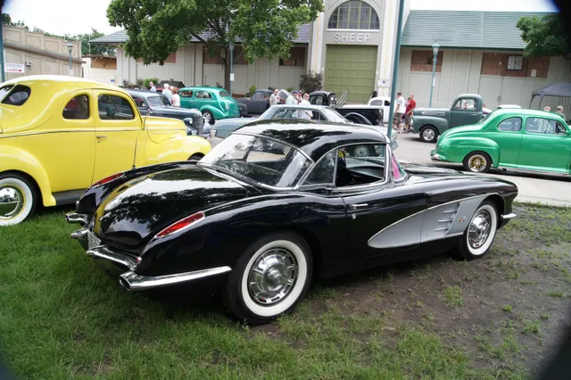 Rear three-quarter view of the Tuxedo Black hardtop car, showing the clean trunk, rear lamps, split bumpers, and hardtop profile.