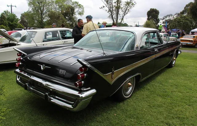 Rear three-quarter hardtop view documenting the fins, three-lens taillights, gold check-mark sweep, deck-lid bars, badging, bumper, and hardtop roof.