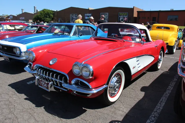 Stock-presenting Roman Red 1960 Corvette with Ermine White coves and white soft top, shown at a public display.