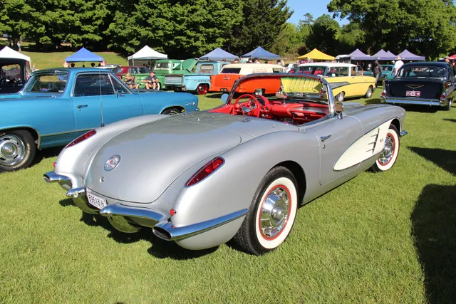 Stock-presenting Sateen Silver 1960 Corvette in rear three-quarter view with Ermine White coves and red interior.