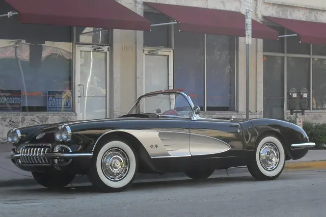 Tuxedo Black 1960 Corvette with Sateen Silver coves in side-front view, illustrating the roadster proportions and factory-style wheel treatment.
