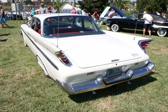 Four-door hardtop rear three-quarter view showing the canted fins, boomerang lamp housings, deck, scripts, bumper, pillarless roof, and body-side treatment.