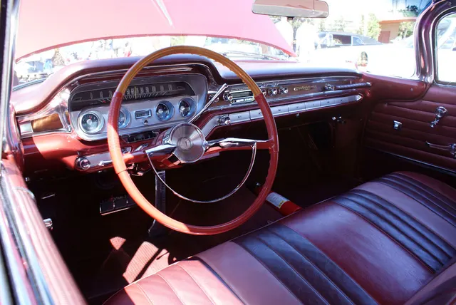 Restored 1960 Bonneville Sport Coupe cabin showing the dashboard, steering wheel, instruments, radio, controls, bench seat, and door trim; colors, materials, and accessories remain specific to the photographed car.