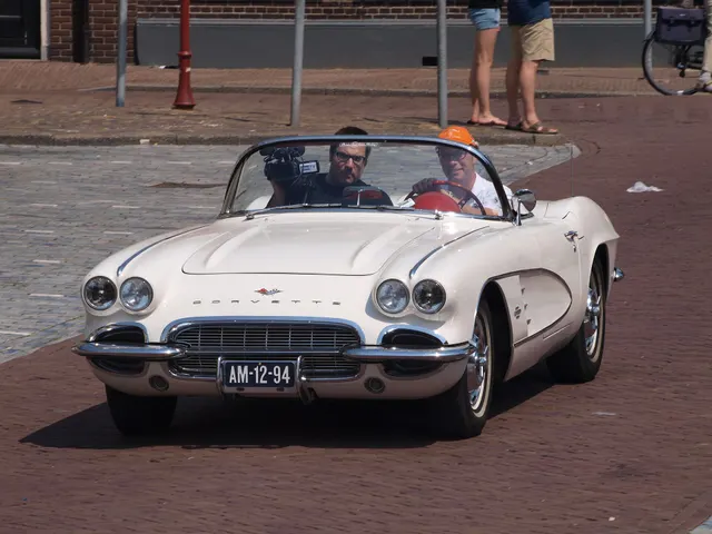 Stock-presenting Ermine White 1961 Corvette photographed in motion with its soft top down.