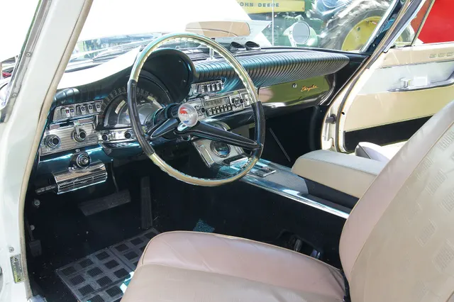 Exact-year hardtop cabin showing the tan bucket seats, full-length console, AstraDome instrument panel, steering wheel, and interior trim.