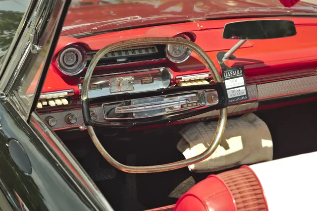 Restored 1961 Fury cabin showing the dashboard, horizontal speedometer, instrument pods, push-button controls, steering wheel, bright trim, and front seat; fuzzy dice, display items, colors, and restoration details are car-specific.