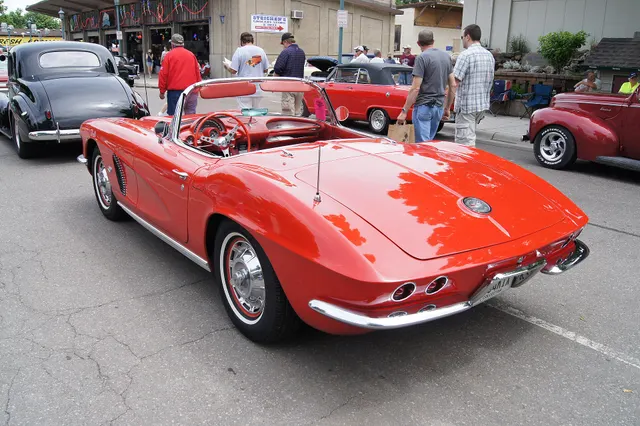 Roman Red 1962 Corvette in rear three-quarter view, showing the external trunk, four round taillamps, and split bumpers.