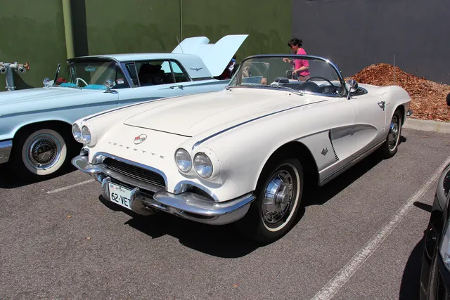 Ermine White 1962 Corvette with its hood open in front three-quarter view; retained as restoration and engine-bay access context.