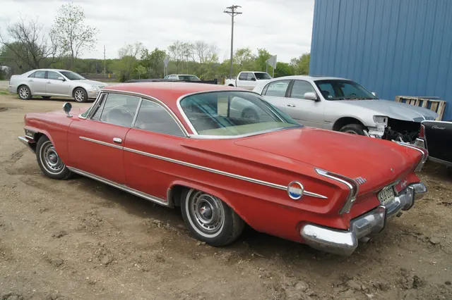 Rear-side view showing the roof transition, wraparound rear glass, deck treatment, quarter medallion, side trim, and wheel cover.