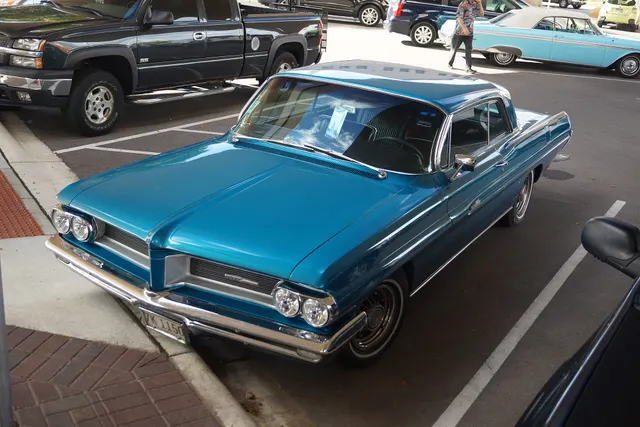 Exact-year Grand Prix view showing paint, side brightwork, grille, lamp bezels, bumpers, wheel covers, and badging; condition and restoration details remain specific to the photographed car.
