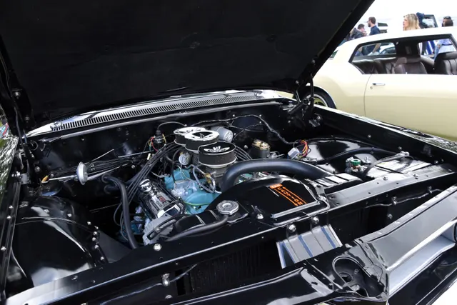 Restored 1962 Grand Prix engine bay showing a 421 Tri-Power installation, air-cleaner arrangement, valve covers, brake booster, radiator, and underhood layout; finishes, service hardware, and restoration details remain specific to the photographed car.