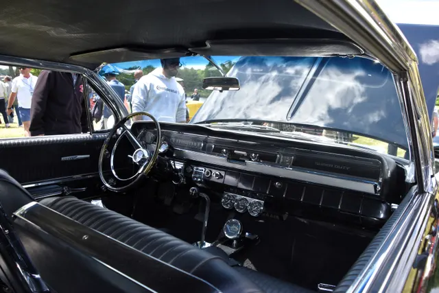 Restored 1962 Grand Prix cabin showing the dashboard, instrument cluster, steering wheel, center console, shifter, bucket seats, and door trim; auxiliary gauges, finishes, accessories, and restoration details remain specific to the photographed car.