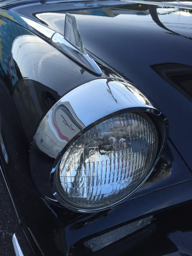 Close detail of the headlamp nacelle, hood contour, fender edge, and factory black finish; useful for separating original form from later trim changes.