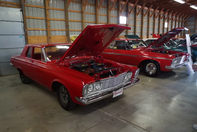 Open engine-bay view of the same 1963 Savoy Max Wedge display, with a Sport Fury visible behind it.