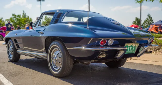 Restored Daytona Blue 1964 coupe in rear three-quarter view, showing the one-piece rear glass, roof vents, and fastback body.