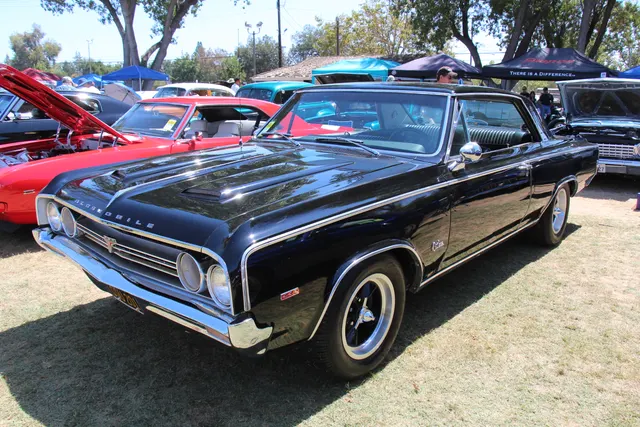 Black 1964 4-4-2 hardtop with non-stock hood and wheels, retained as clearly labeled restoration context