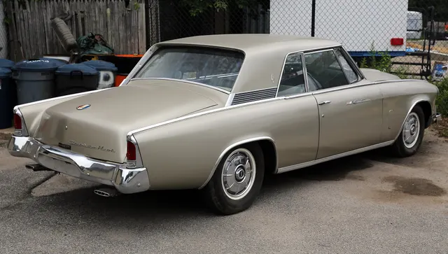 Rear three-quarter view documenting the smooth final-year deck lid, chrome Studebaker Hawk script, fully chromed tail-lamp housings, bumper, dual exhaust, roof, and body proportions.