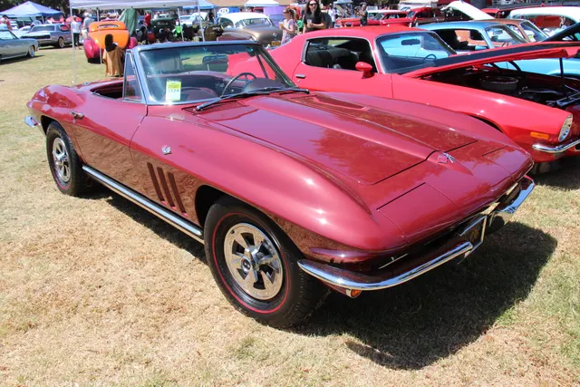 Restored Rally Red convertible in front three-quarter view with the top lowered and optional-style cast-aluminum wheels.