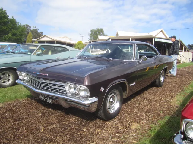 Dark-finish 1965 Impala SS Sport Coupe showing the 396 emblem, hardtop roofline, bucket-seat cabin, and stock-style steel wheels