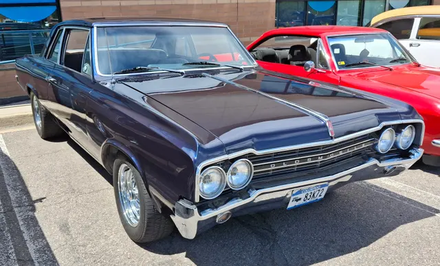 Dark 1965 Oldsmobile hardtop with later wheels; retained only as clearly labeled body context