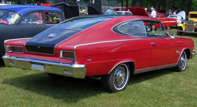 Rear three-quarter view of an Antigua Red and Classic Black exact-year car showing the roof and insert treatment, side trim, Marlin emblems, wheel covers, and body proportions.