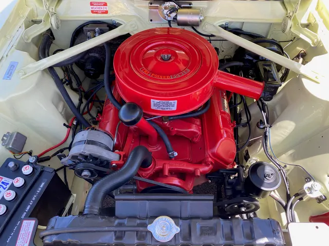 Restored exact-year 327 engine bay showing the Tri-Poised Power air cleaner, V8 installation, alternator, cooling layout, brake hardware, shock towers, and factory-style braces.