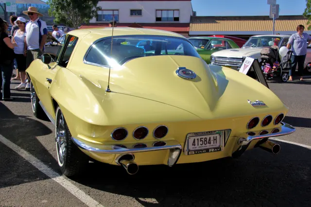 Rear view of the Sunfire Yellow coupe, documenting the 1966 taillamp, bumper, fuel-door, and roof treatment.