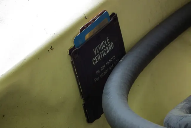 Survivor-context view of a vehicle certification card holder retained to show why original paperwork matters; the photographed card is not readable evidence for another car.