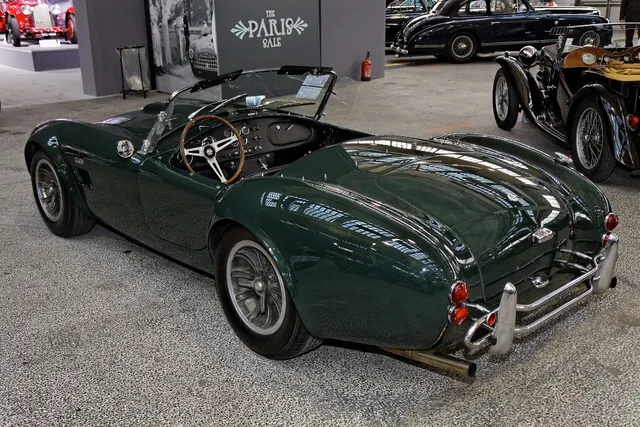 Rear three-quarter view of the green street roadster showing the road-car tail, bumper hardware, cockpit opening, and center-lock wheels.