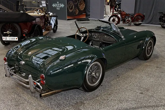 High rear three-quarter view showing the street cockpit, deck, fuel-filler area, windscreen, and wheel stance without claiming universal trim.
