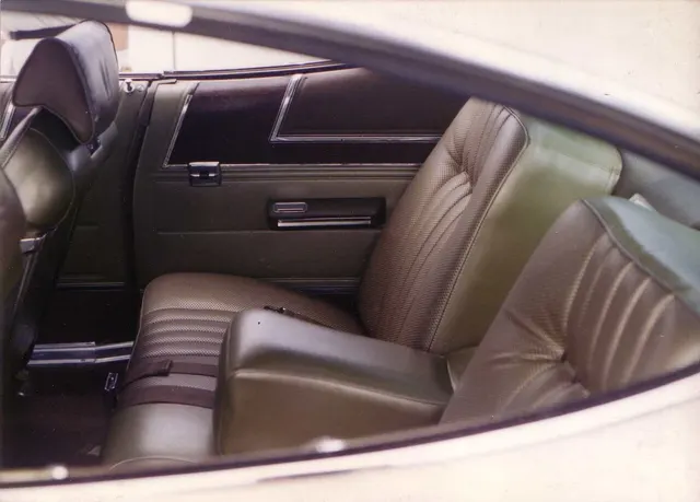 Exact-year cabin view showing the reclining front seat, rear seat, fold-down armrests, upholstery, side panel, and pillarless window opening.
