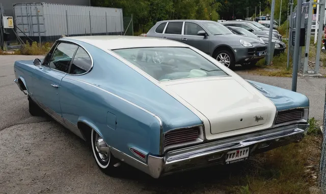Rear three-quarter view of the same stock-presenting car showing the long fastback glass, contrasting roof and deck treatment, tunneled tail lamps, bumper, Marlin deck script, wheel covers, and body proportions.